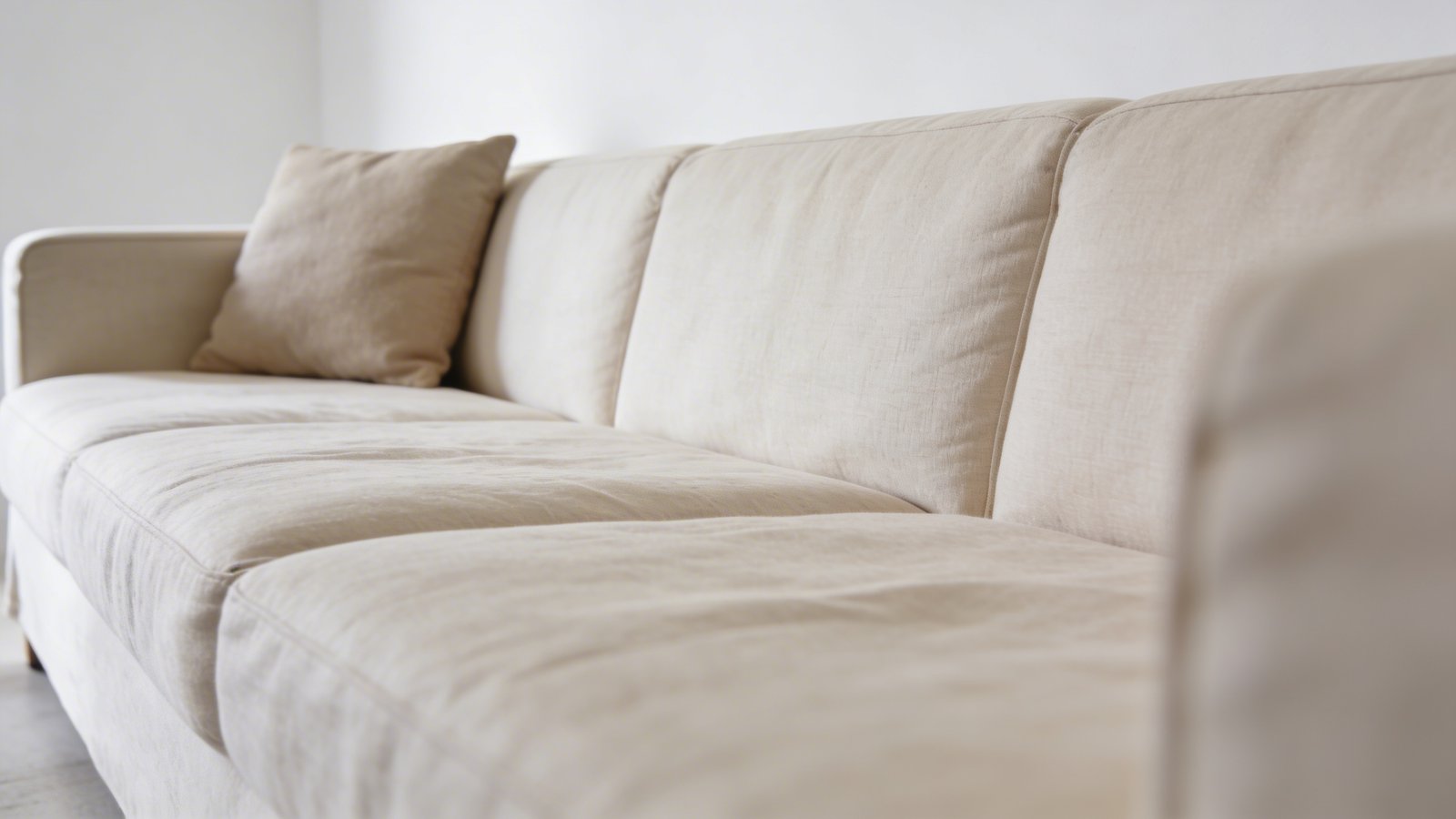 Modern beige linen sofa against white wall